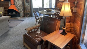 A cozy cabin interior with a fireplace, wooden furniture, and a dining area. - Cozy Mountain Paradise (Kamas)