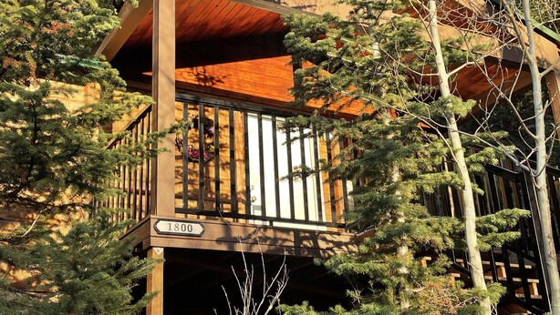 A multi-story building with a wooden balcony, surrounded by trees. - Cozy Mountain Paradise (Kamas)