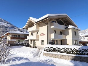 A multi-story building with a sign reading 'Apart Panorama' in a snowy mountainous area.