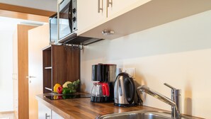 Een moderne keuken met een roestvrijstalen spoelbak, een houten aanrechtblad en een inbouw magnetron.