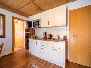 A modern kitchen with white cabinets, a wooden ceiling, and a stainless steel sink. - Charming apartment in quiet location (Mayrhofen)