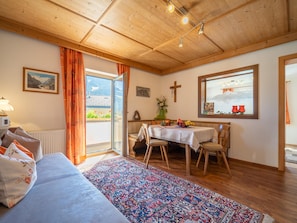 A cozy room with a bed, a dining table with chairs, a window with a view of mountains, and a wooden ceiling. - Charming apartment in quiet location (Mayrhofen)