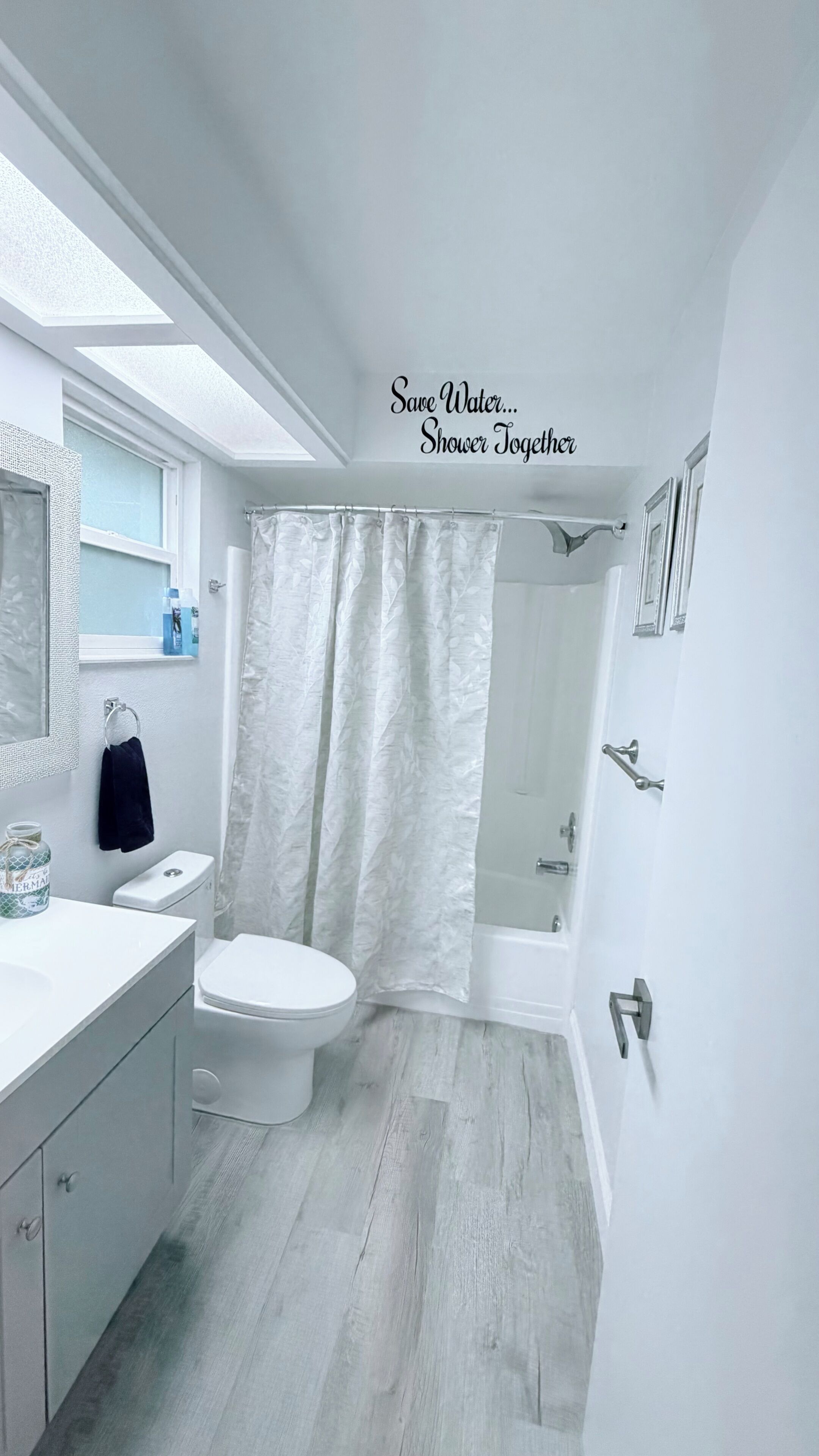 A modern bathroom with a skylight, a toilet, a shower, and a vanity.