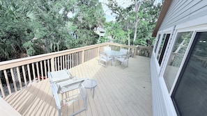 A wooden deck with a table and chairs, surrounded by trees.