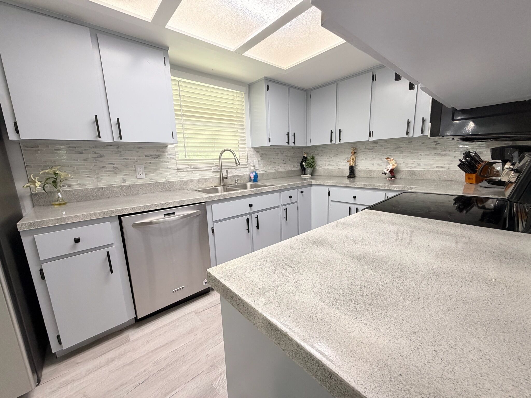 A modern kitchen with white cabinets, a dishwasher, a sink, and a countertop.