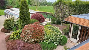 Een verzorgde tuin met diverse struiken en een conservatorium.