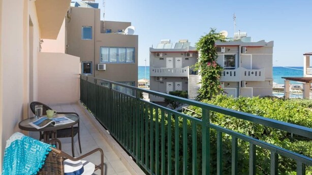 Un balcón con vistas al mar, una mesa con sillas y un pequeño jardín.