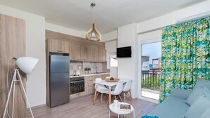 Una cocina moderna con armarios de madera, un refrigerador de acero inoxidable y una zona de comedor con sillas blancas y una pequeña mesa.