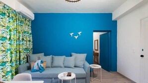 Una sala moderna con una pared azul decorativa, un sofá, una mesa de centro y una cortina estampada.