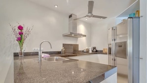 Una cocina moderna con encimeras de granito, electrodomésticos de acero inoxidable y un ventilador de techo.