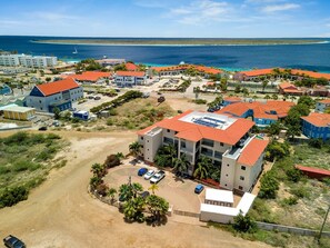 A coastal hotel with multiple buildings, a parking area, and a view of the ocean.
