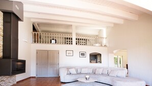 A spacious living area with a large L-shaped sofa, a round coffee table, and a fireplace.
