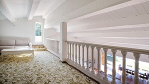 A spacious room with a patterned carpet, a white sofa, and a balcony with white railings.