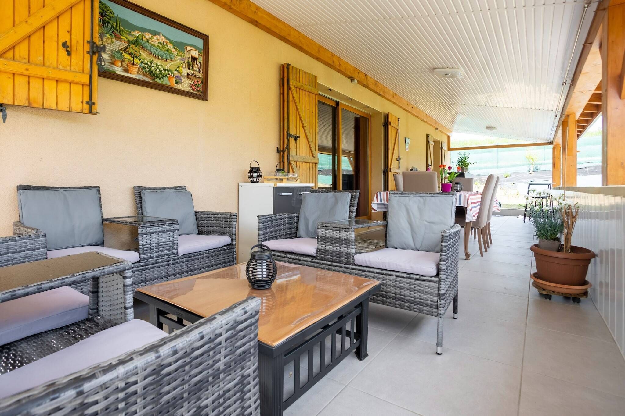 A covered outdoor seating area with wicker furniture and a view of the garden.