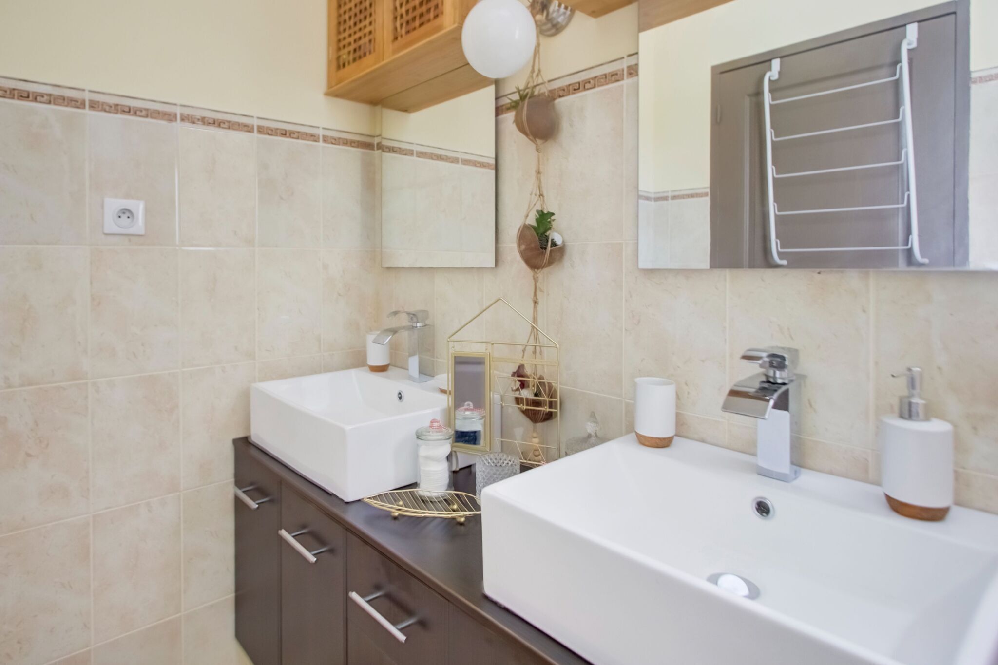Un baño moderno con dos lavamanos, un espejo y un perchero para toallas.