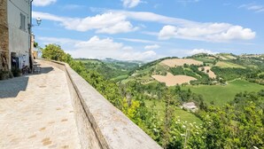 Un sentier pavé de pierres mène à un bâtiment d’où l’on peut admirer des collines ondoyantes et un ciel dégagé.