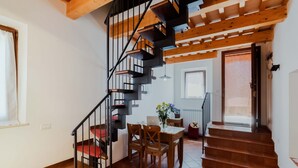 A staircase with a wooden finish and black railings, leading to a dining area with a table and chairs.
