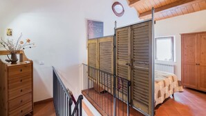 A bedroom with a wooden ceiling, a bed with a quilt, a dresser, and a window.