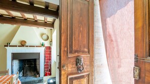 A wooden door with a metal handle, a fireplace with a brick surround, and a checkered tablecloth. - Holiday home in Torchiaro with garden (Torchiaro)