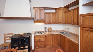 Una cocina con armarios de madera, estufa y lavamanos.