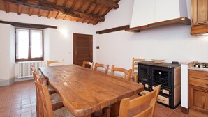 Un comedor con una mesa y sillas de madera, una estufa negra y un armario blanco.