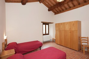 Una habitación con dos camas, un armario de madera, una silla y un ventanal con vistas.