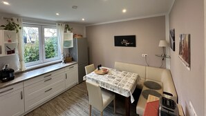 A compact kitchen with a dining area, featuring a window, built-in shelves, a refrigerator, a table with a tablecloth, and a toaster. - Bright, modern, large vacation apartment on a south-facing slope in a climatic health resort (Friedrichroda)