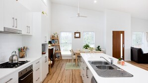 A modern kitchen with white cabinets, a gas stove, and a large island with a sink. - Break Away in Dolphin Point (Dolphin point)