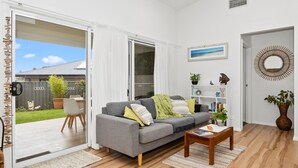 A modern living room with a grey sofa, a wooden coffee table, and a bookshelf. - Break Away in Dolphin Point (Dolphin point)