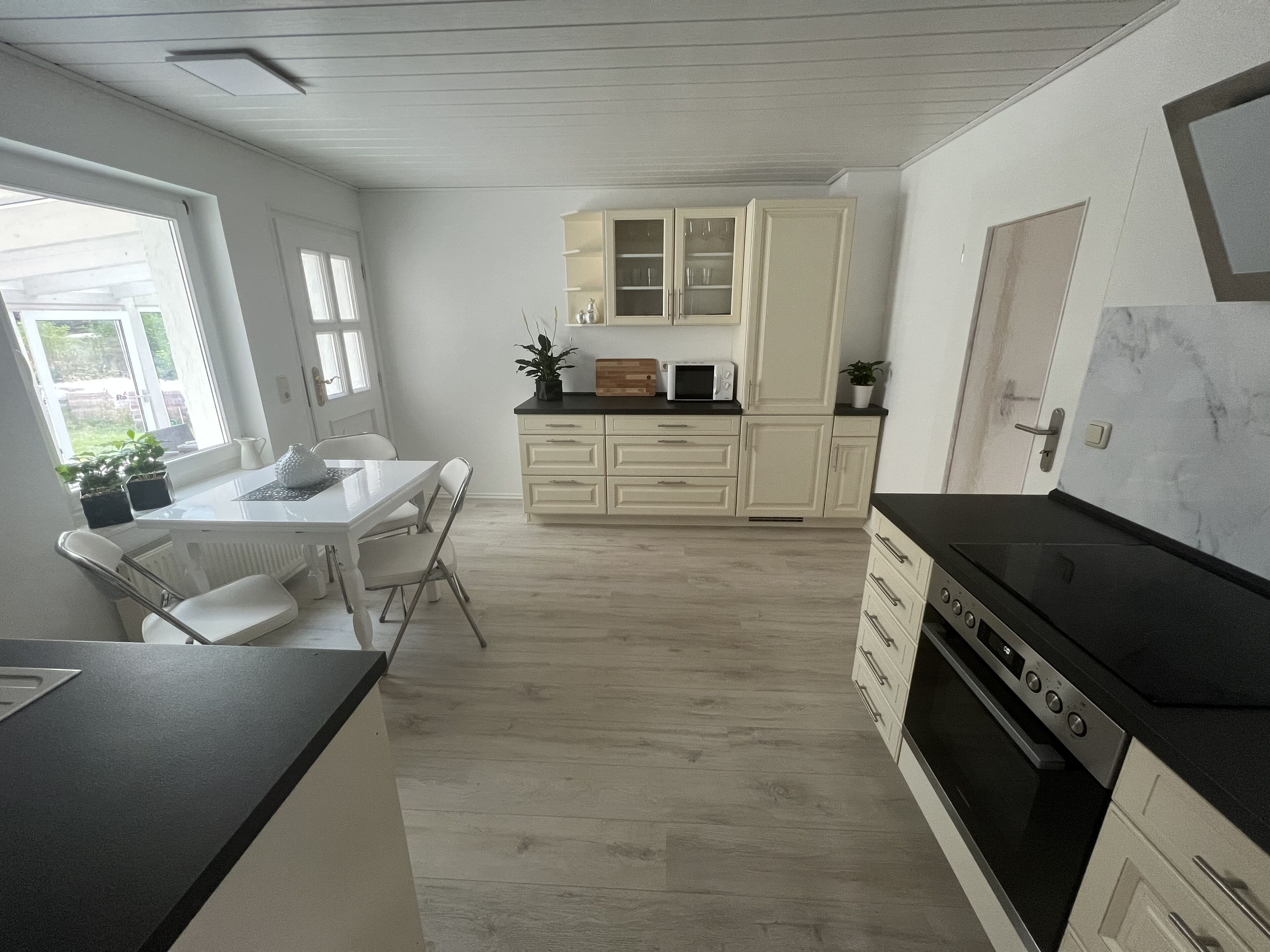 Une cuisine moderne avec des meubles blancs, un plan de travail noir et un four encastré.