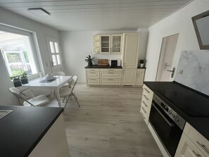 Una cocina moderna con armarios blancos, encimera negra y horno empotrado.