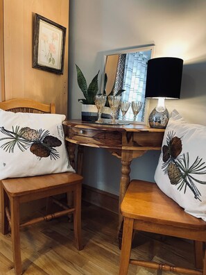 A wooden dining table with a lamp, two chairs, and a decorative plant.