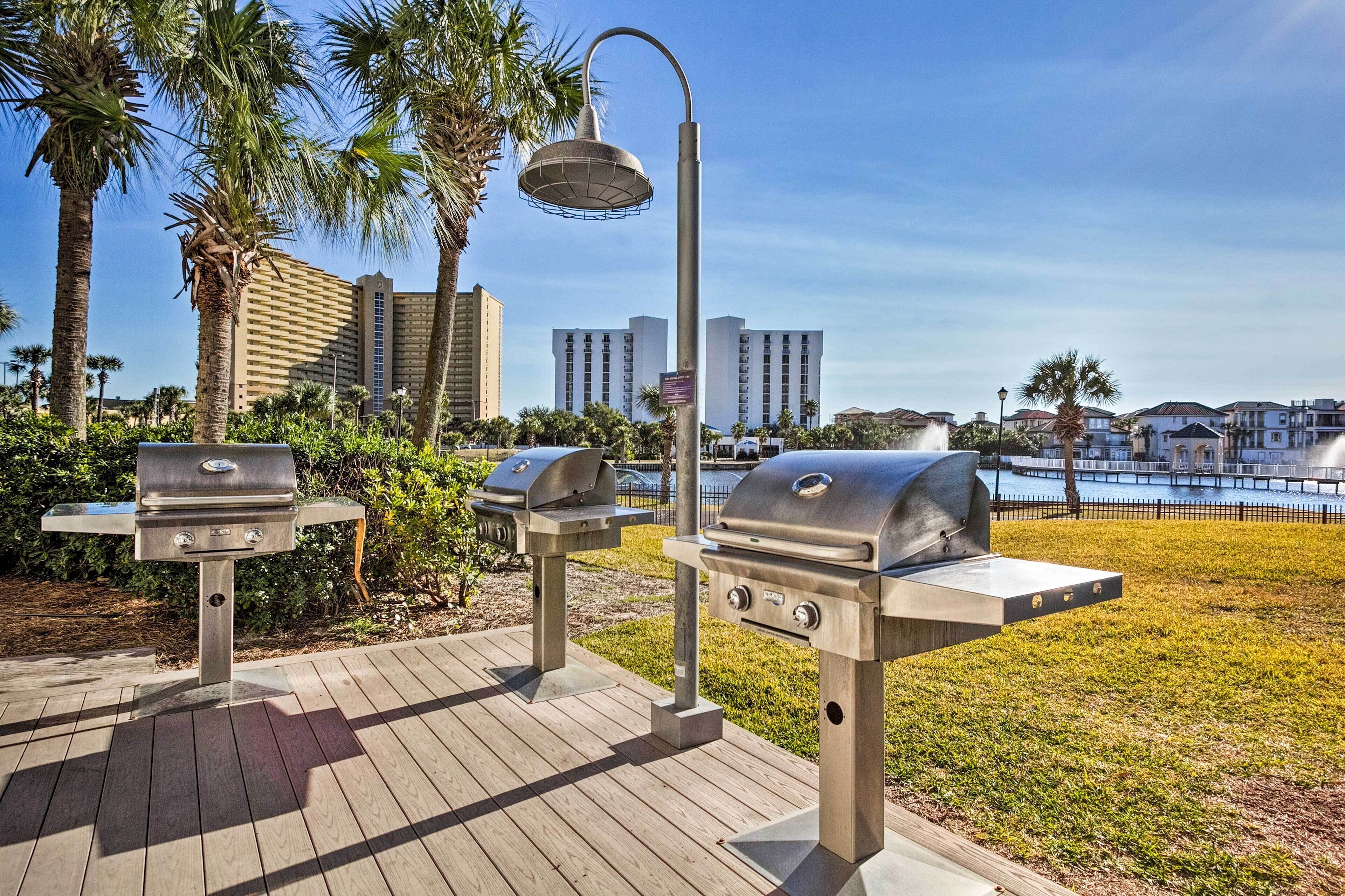 Des barbecues d’extérieur, une terrasse en bois et une vue sur une étendue d’eau, avec des bâtiments en arrière-plan.