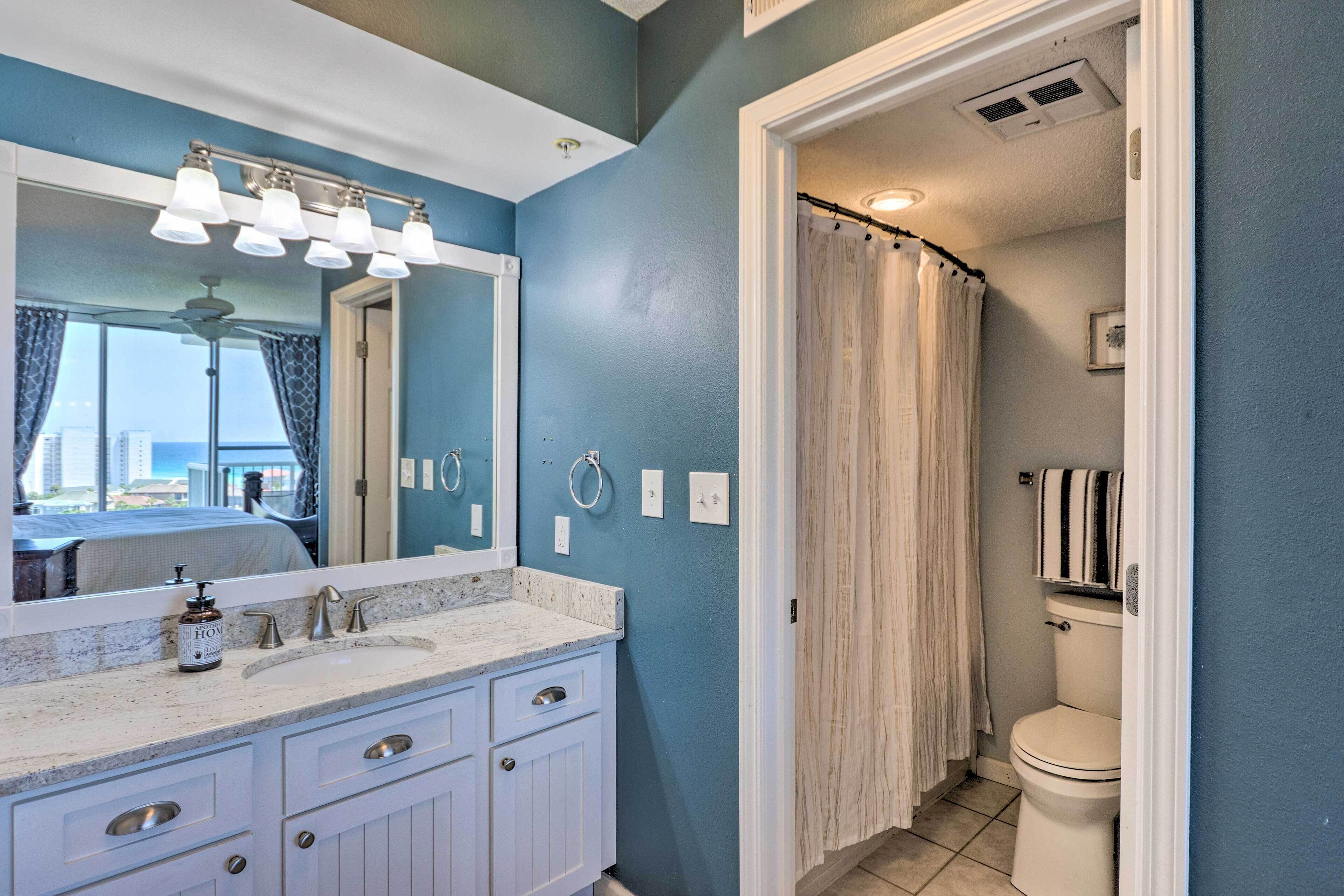 A bathroom with a blue wall, white vanity, and a shower curtain.