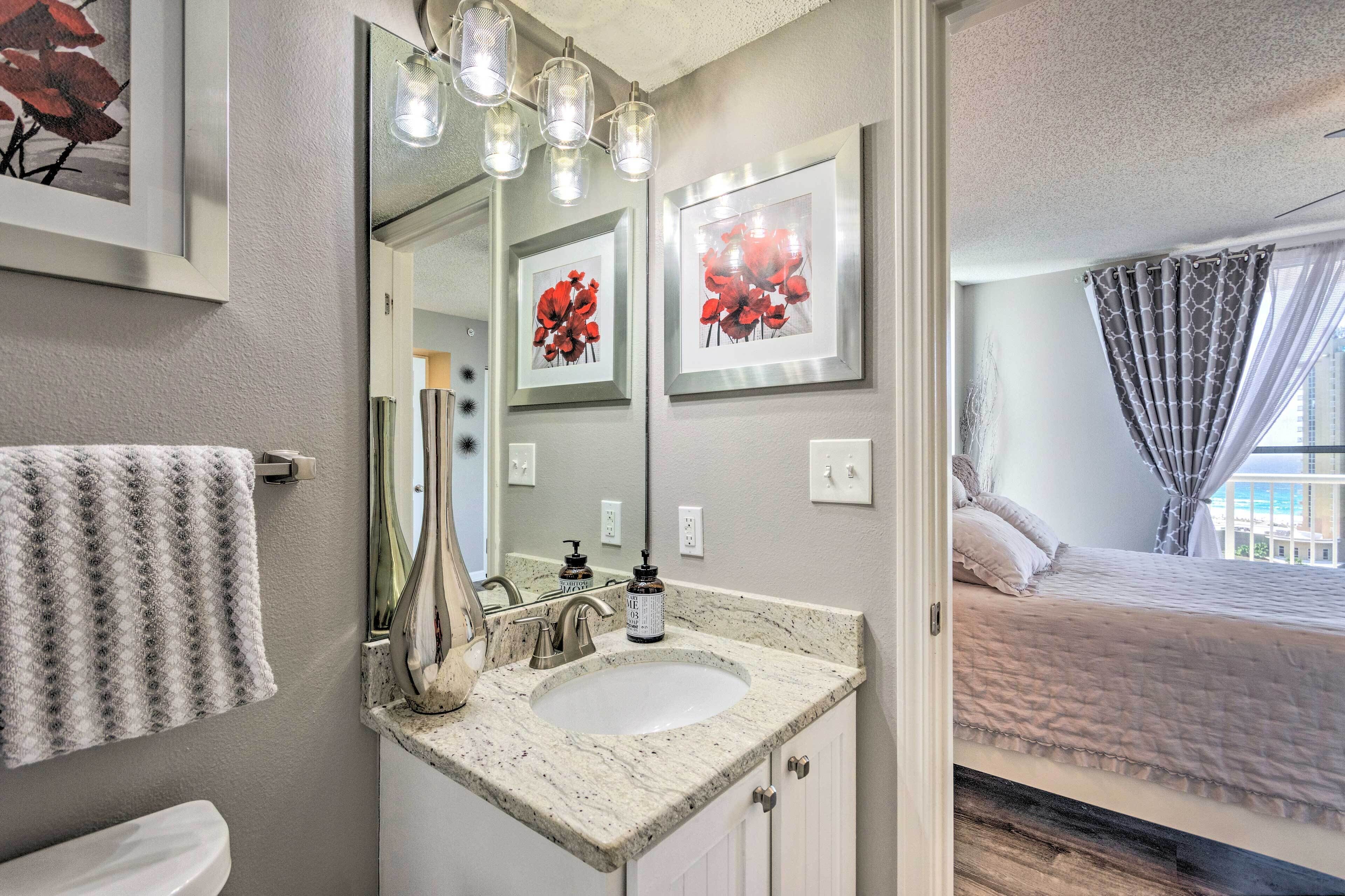 A bathroom with a sink, mirror, and framed artwork.