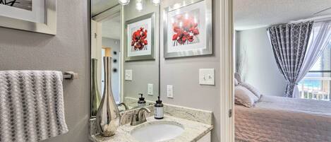 A bathroom with a sink, mirror, and framed artwork.