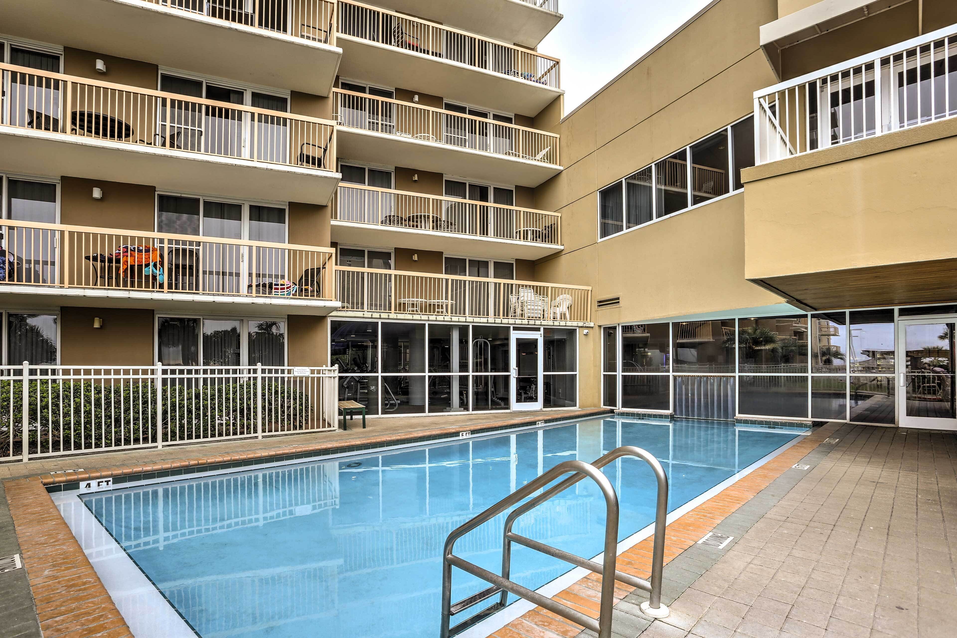 A multi-story building with a swimming pool, balconies, and large windows.