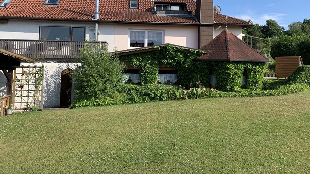 Una casa de dos pisos con techo de tejas, una chimenea y un pequeño balcón.