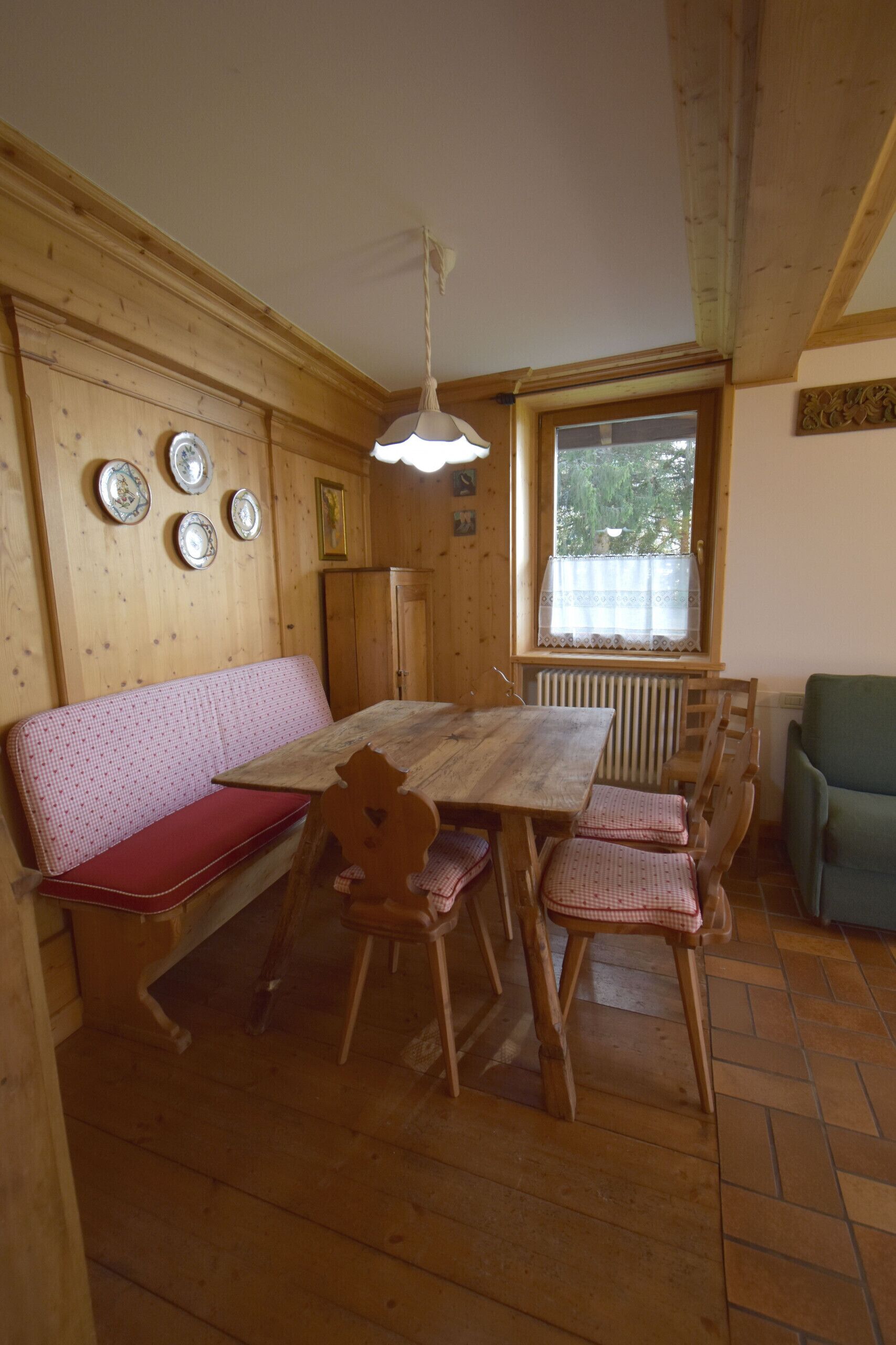 A wooden dining area with a bench, table, and chairs.