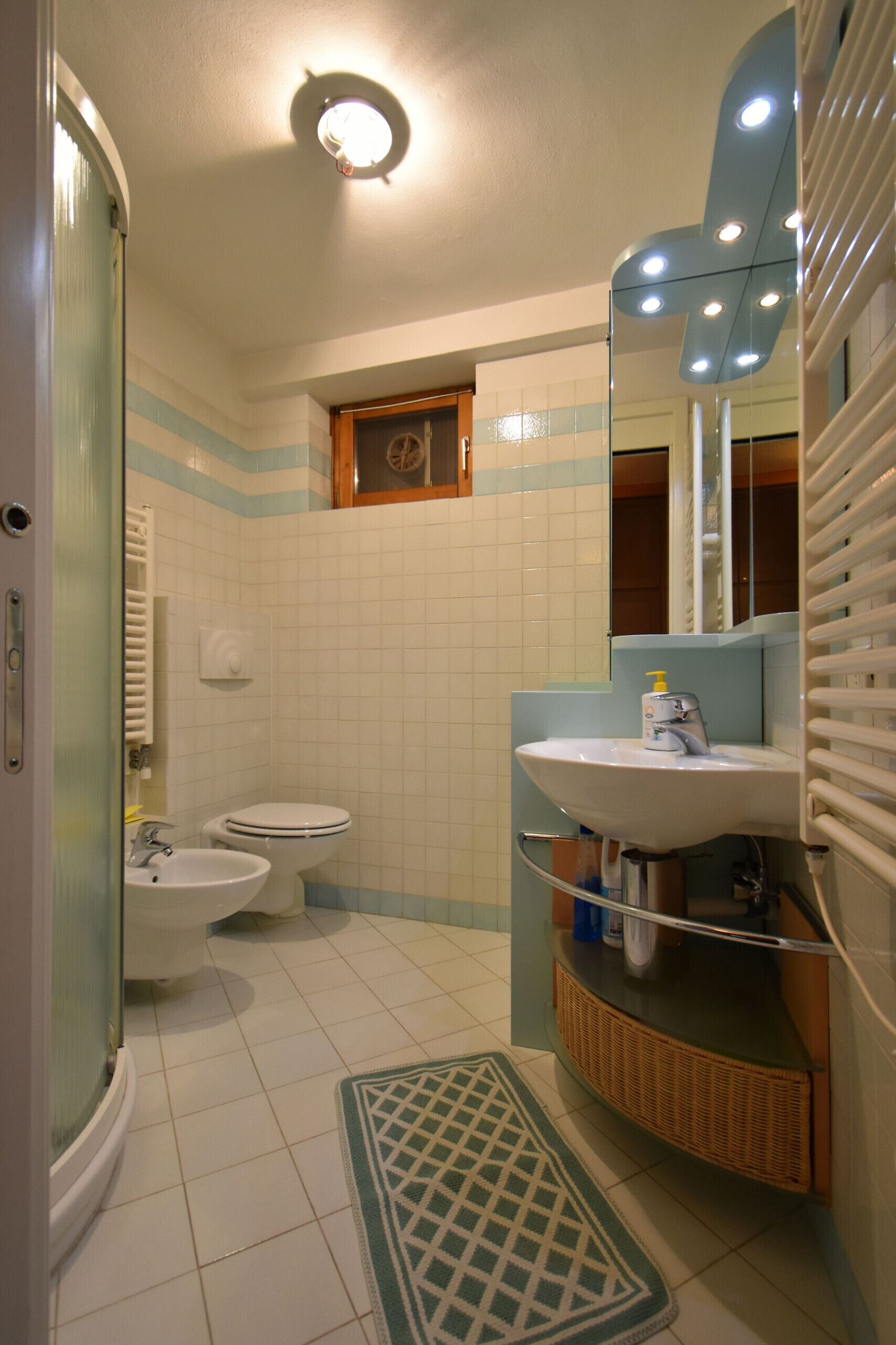 Un baño con inodoro, bidé, lavamanos y espejo.