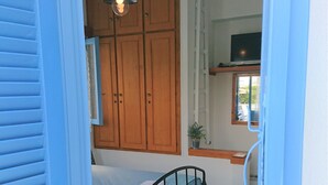 Une chambre à coucher avec un lit, une armoire en bois et un luminaire suspendu.