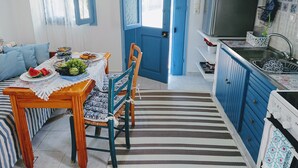 Un coin repas avec une table dressée pour deux personnes, une porte bleue et une cuisine avec des meubles bleus.