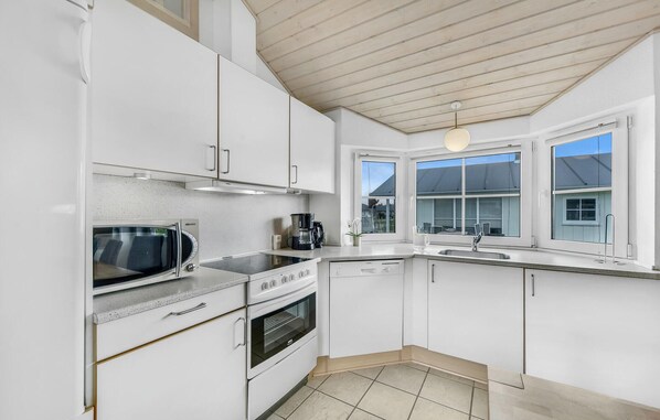 A modern kitchen with white cabinets, a built-in oven, a microwave, and a coffee maker.