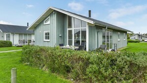 Een modern huis met twee verdiepingen, grote ramen, een overdekt terras en een verzorgd gazon.