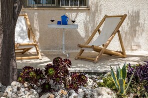 Deux fauteuils de relaxation en bambou, une petite table avec deux verres à vin et une carafe, ainsi qu’une variété de plantes succulentes.
