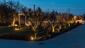 A nighttime view of a park with trees, a gazebo, and a building with a dome-shaped roof. - Holiday Home 'Trulli Terralunga' with Pool and Wi-Fi (Martina Franca)