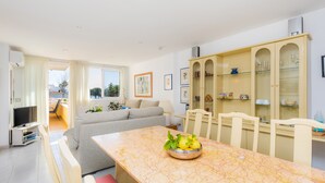 Een moderne woonkamer met een eettafel, een bank en een keuken met kasten.