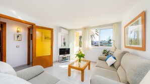Een moderne woonkamer met een bank, salontafel, televisie en uitzicht op zee.