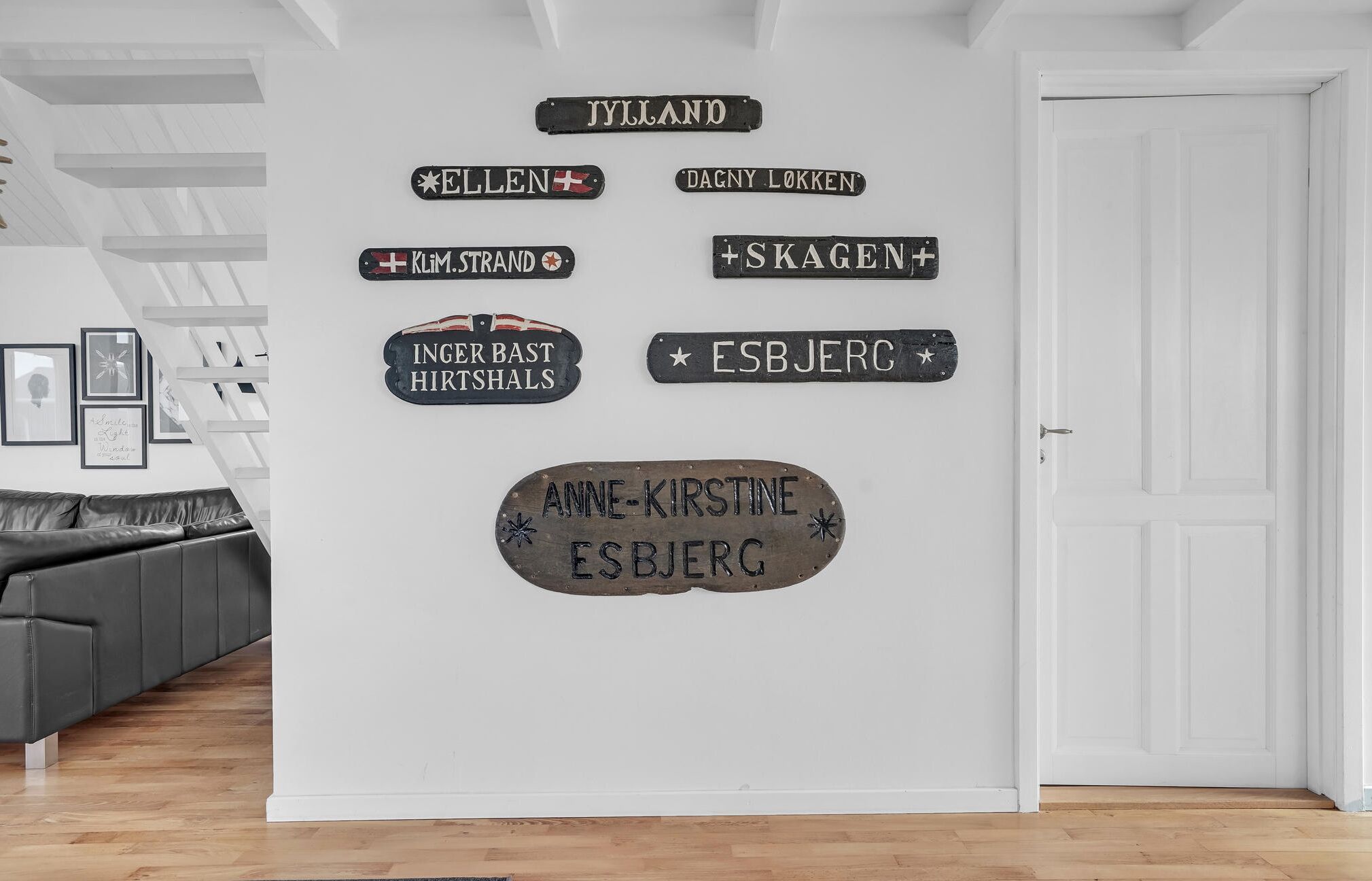 Un mur orné de divers panneaux, notamment les inscriptions « Jylland », « Ellen », « Dagny Løkken », « Klim. Strand », « Skagen », « Inger Bast Hirtshals », « ESBJERG » et « Anne-Kirstine ESBJERG ».