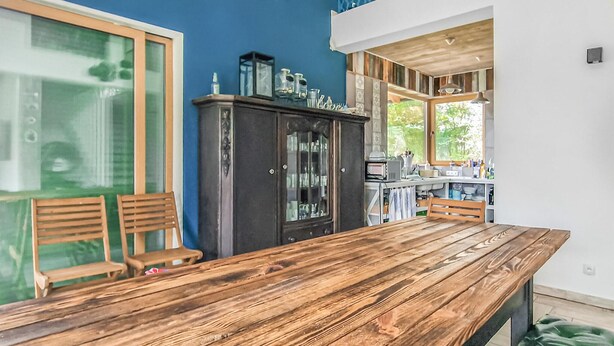 Un coin repas comprenant une table en bois, deux chaises en bois, un buffet en bois foncé et une fenêtre donnant sur un paysage verdoyant.